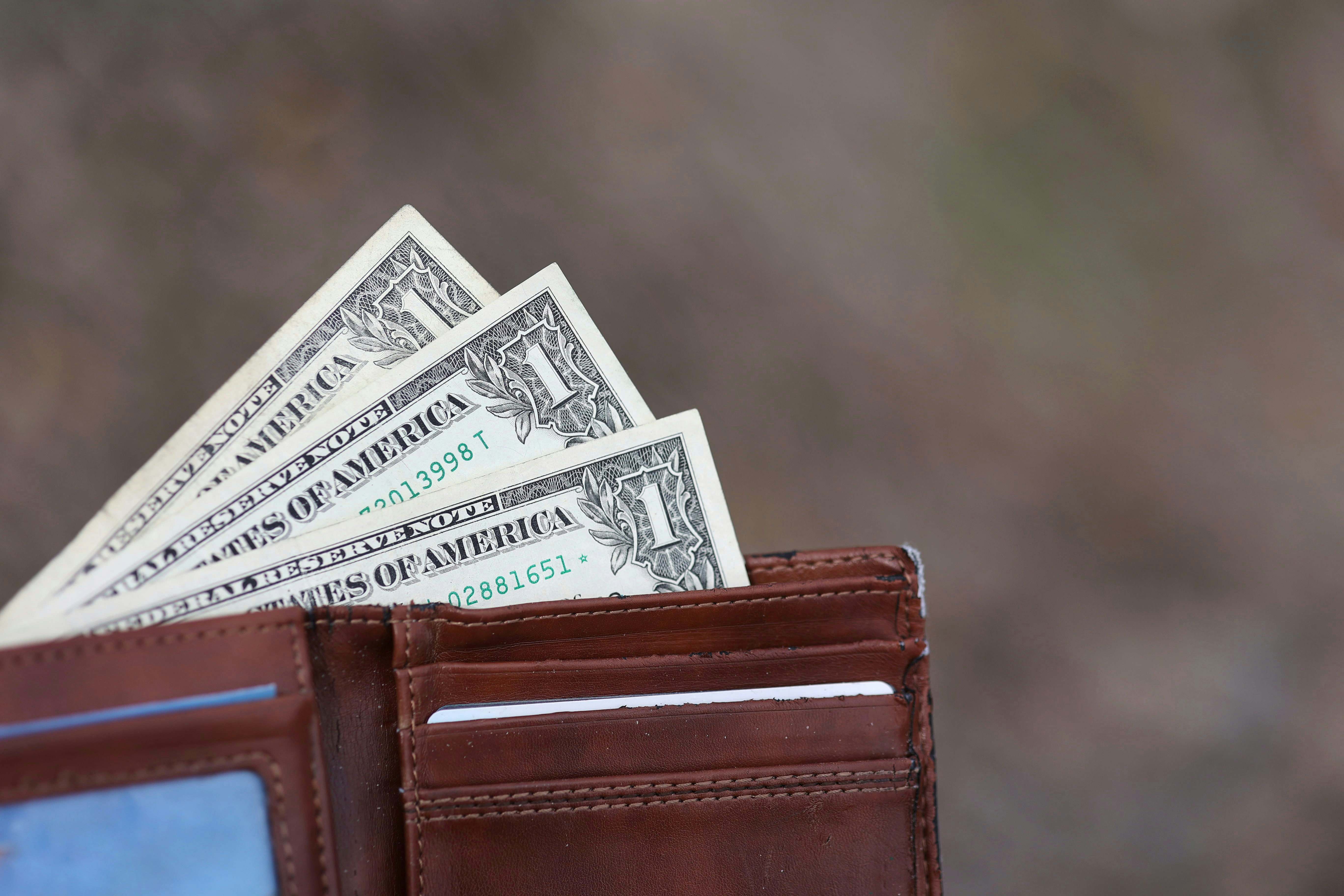 a wallet with five dollar bills sticking out of it